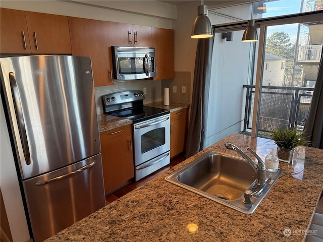 kitchen with stainless steel appliances, decorative backsplash, pendant lighting, and sink