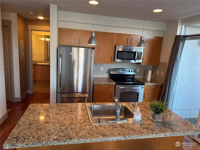 kitchen featuring dark wood-type flooring, hanging light fixtures, stainless steel appliances, backsplash, and sink