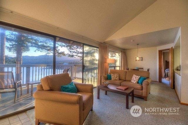 tiled living room featuring vaulted ceiling and a water view