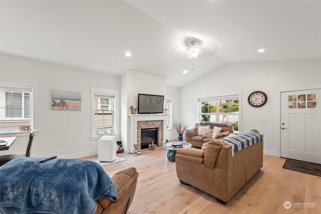 living room with vaulted ceiling, a fireplace, ceiling fan, and light hardwood / wood-style floors