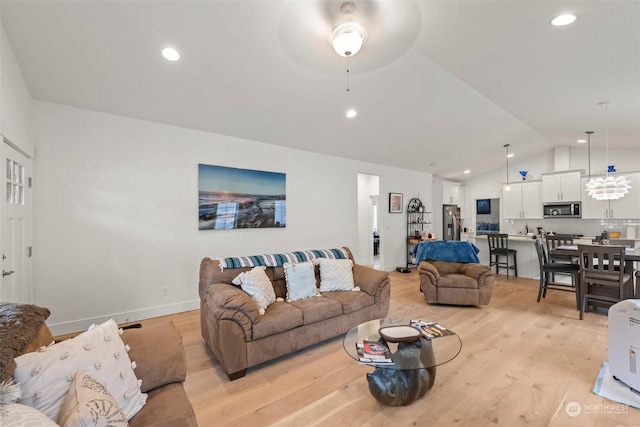 living room with lofted ceiling, ceiling fan, and light hardwood / wood-style floors