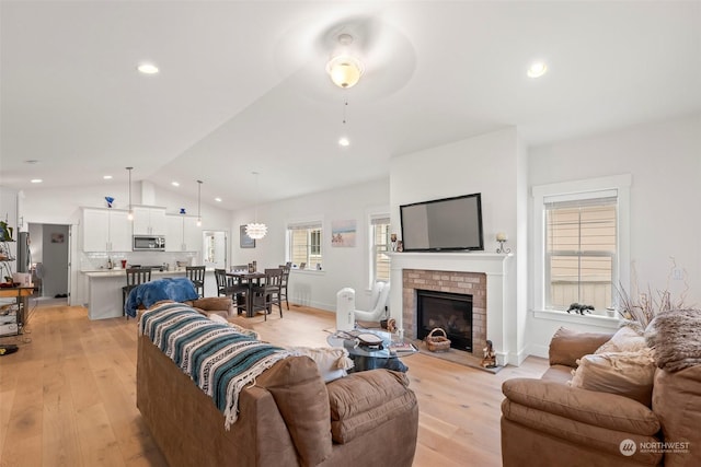 living room featuring light hardwood / wood-style floors, a fireplace, ceiling fan, and plenty of natural light