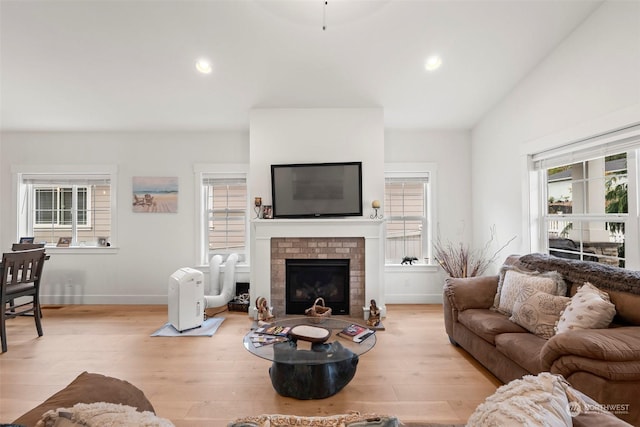 living room featuring lofted ceiling, a fireplace, and light hardwood / wood-style floors