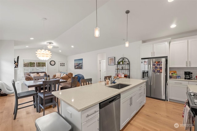 kitchen with vaulted ceiling, appliances with stainless steel finishes, hanging light fixtures, white cabinetry, and tasteful backsplash