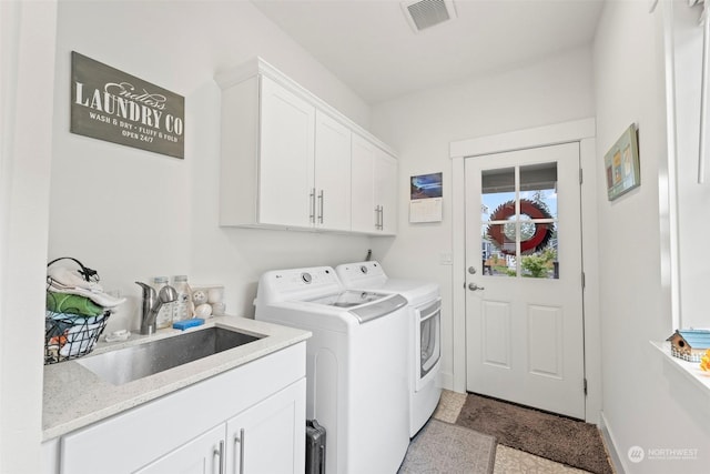 washroom with sink, washing machine and dryer, and cabinets