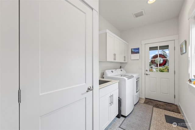 laundry area featuring washing machine and clothes dryer and cabinets