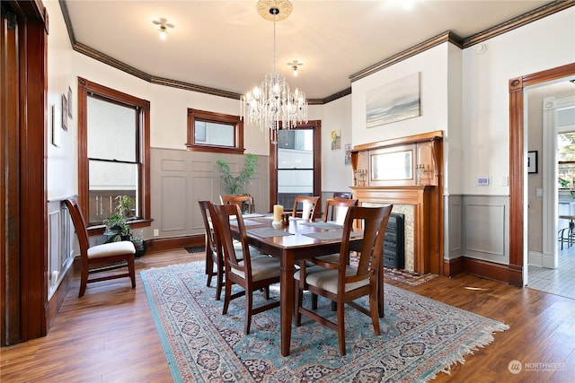 dining area with dark hardwood / wood-style floors, crown molding, and an inviting chandelier