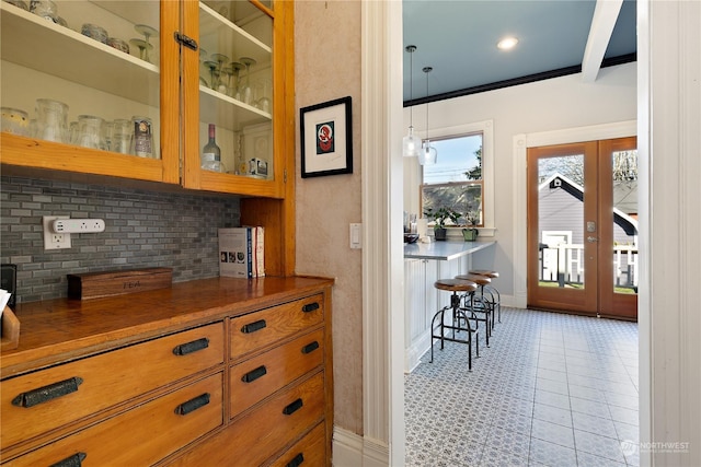 bar featuring ornamental molding, french doors, and tasteful backsplash