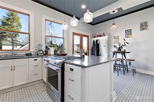 kitchen featuring a wealth of natural light, white cabinets, decorative light fixtures, sink, and high end stainless steel range oven