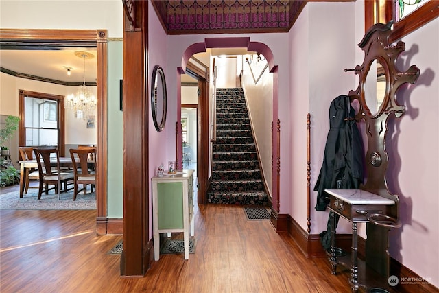 foyer entrance with a notable chandelier, hardwood / wood-style flooring, and crown molding