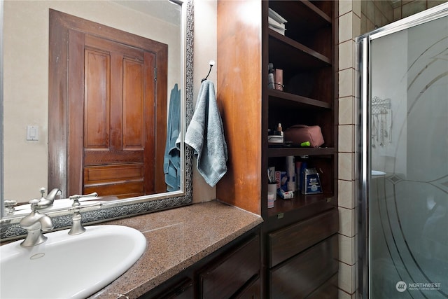 bathroom featuring a shower with door and vanity