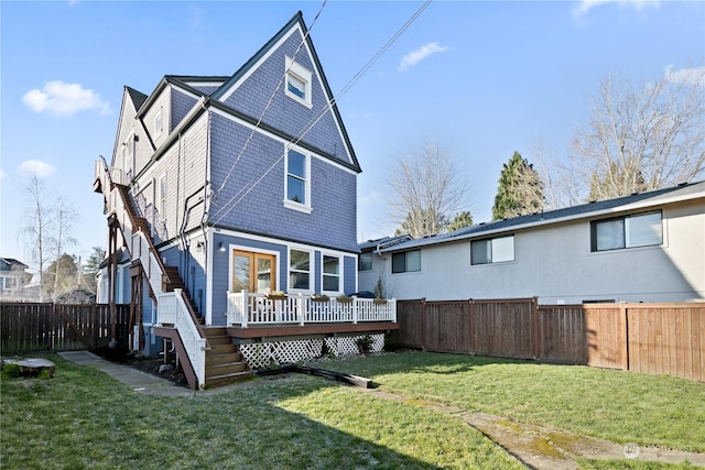 rear view of house featuring a wooden deck and a yard