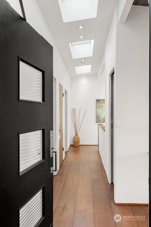 hall featuring a skylight and light hardwood / wood-style flooring