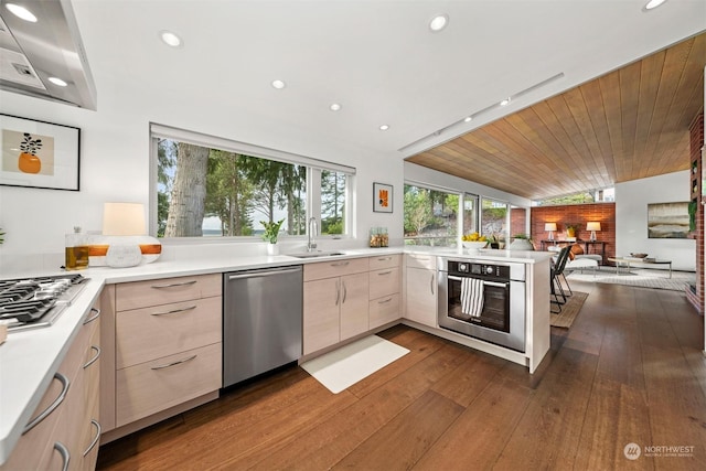 kitchen with stainless steel appliances, light brown cabinets, sink, and kitchen peninsula