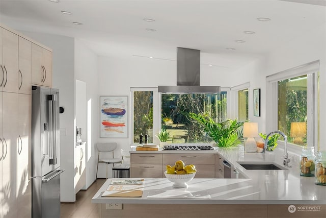 kitchen with kitchen peninsula, island range hood, sink, high end fridge, and light brown cabinets