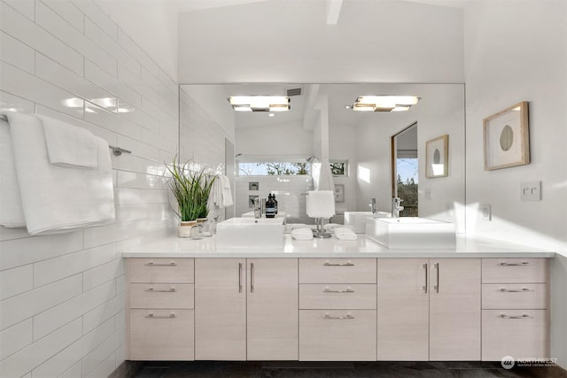 bathroom with tile walls, walk in shower, lofted ceiling, and vanity