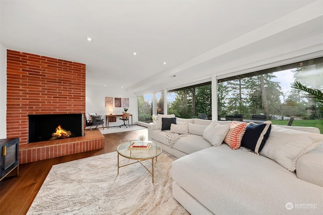 living room with a brick fireplace and wood-type flooring