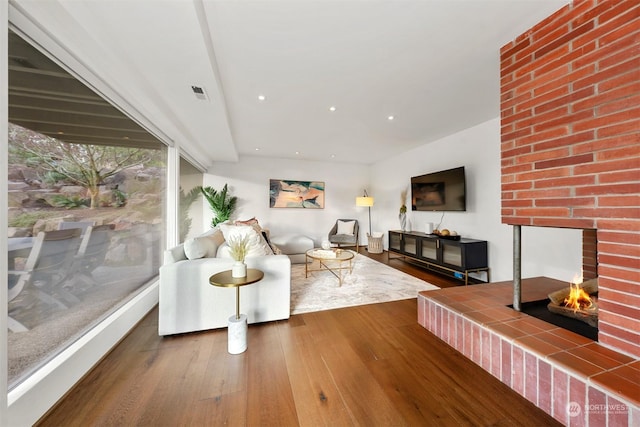 living room with a tile fireplace and hardwood / wood-style floors