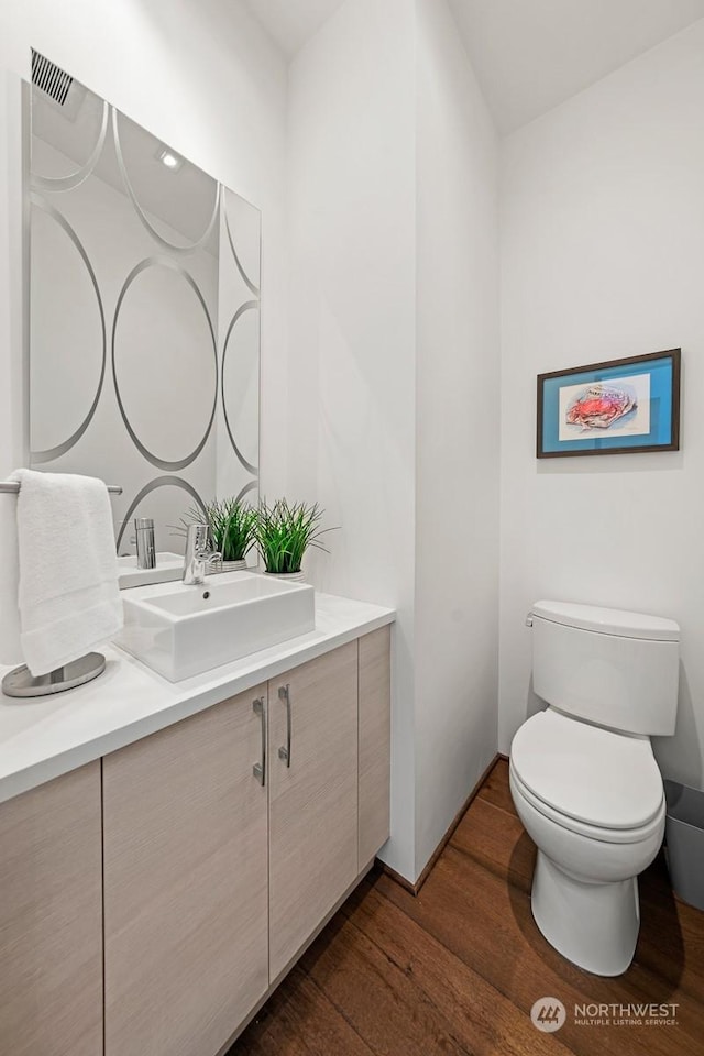 bathroom with toilet, vanity, and hardwood / wood-style flooring