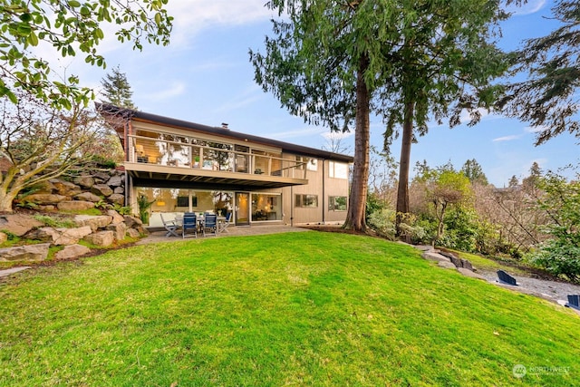 back of house with a deck, a yard, and a patio