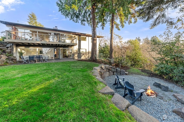 view of yard with a balcony, a fire pit, and a patio