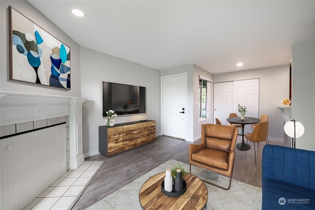 living room with a tiled fireplace and light wood-type flooring