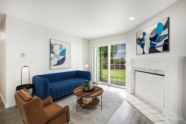 living room featuring a tile fireplace and light wood-type flooring