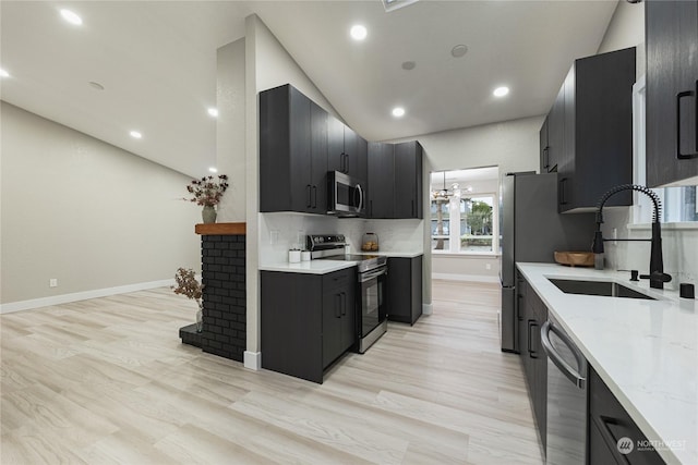 kitchen with light stone counters, stainless steel appliances, light hardwood / wood-style floors, and sink