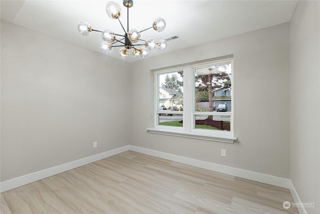 unfurnished room featuring an inviting chandelier and light hardwood / wood-style flooring