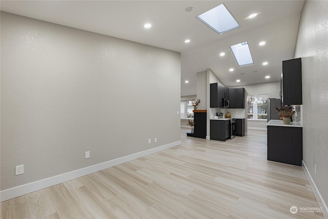 kitchen featuring appliances with stainless steel finishes, light hardwood / wood-style flooring, a skylight, and high vaulted ceiling