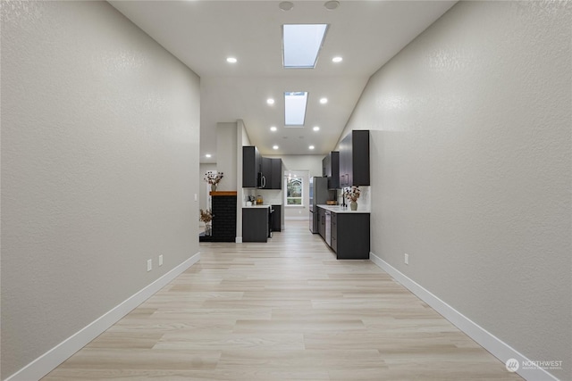 hall featuring a skylight and high vaulted ceiling