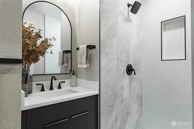 bathroom with vanity and tiled shower