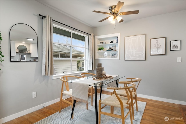 dining space with built in features, hardwood / wood-style flooring, and ceiling fan