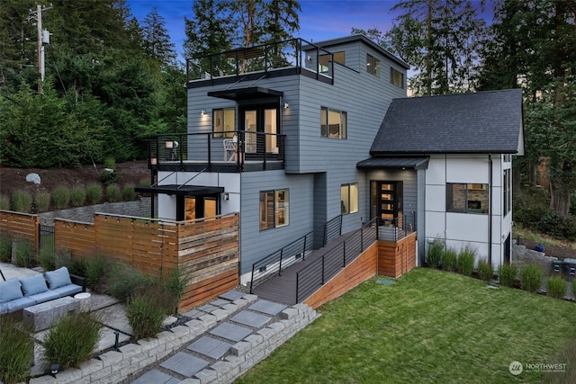 view of front facade with a balcony, a lawn, and an outdoor hangout area