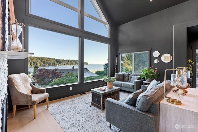 living room featuring a water view, hardwood / wood-style flooring, and high vaulted ceiling