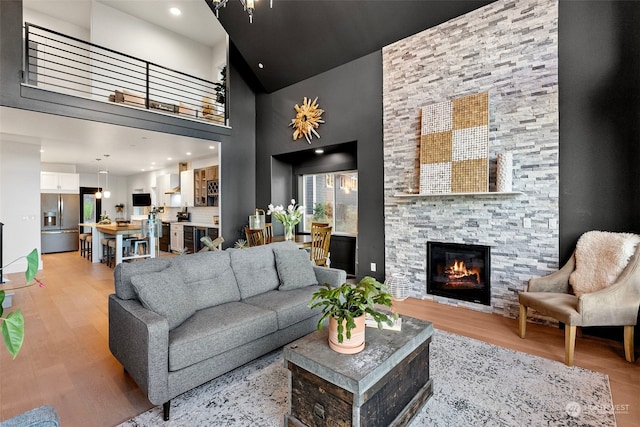 living room featuring light hardwood / wood-style floors, a high ceiling, and a stone fireplace