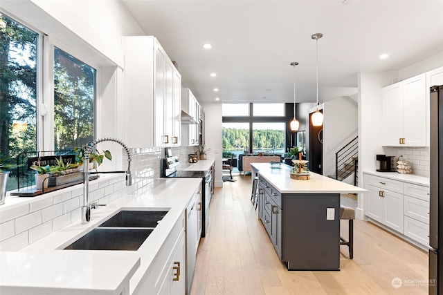 kitchen featuring sink, pendant lighting, white cabinets, and a center island