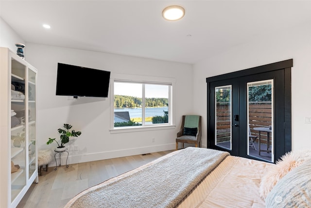 bedroom with wood-type flooring, french doors, and access to outside