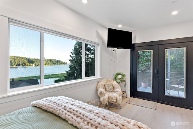 bedroom with a water view, access to outside, french doors, and multiple windows