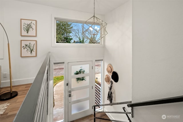 foyer entrance featuring an inviting chandelier, plenty of natural light, and wood-type flooring