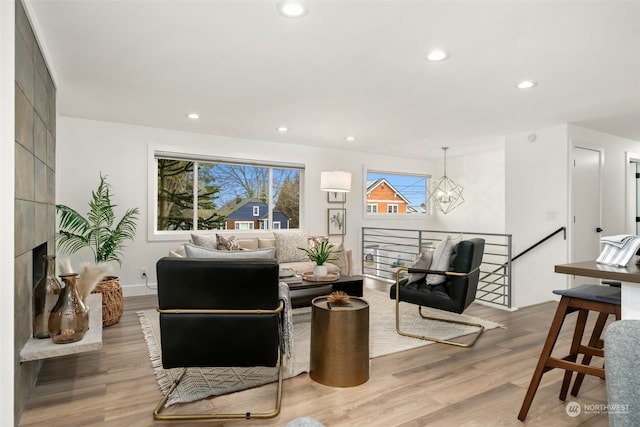 living room featuring a tiled fireplace and light wood-type flooring