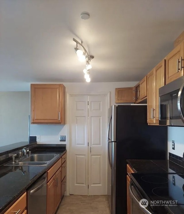 kitchen with appliances with stainless steel finishes, sink, and dark stone countertops