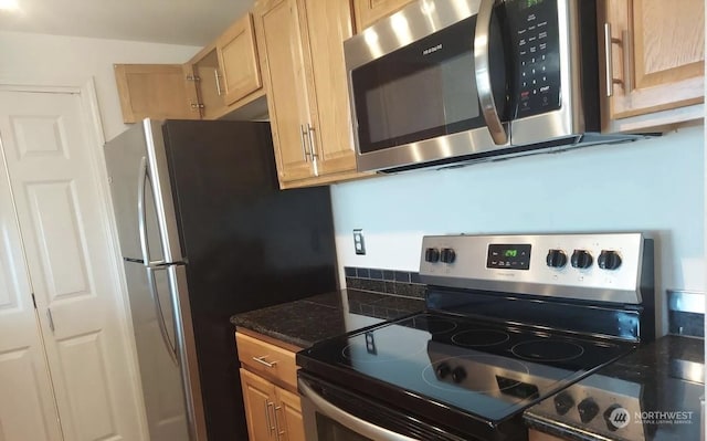 kitchen with light brown cabinetry, dark stone counters, and appliances with stainless steel finishes