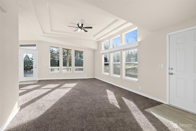 unfurnished sunroom featuring ceiling fan, a healthy amount of sunlight, and a raised ceiling