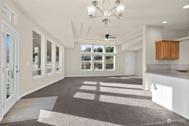 unfurnished living room with ceiling fan with notable chandelier, sink, a raised ceiling, and light carpet