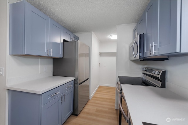 kitchen featuring light wood-type flooring, appliances with stainless steel finishes, and a textured ceiling