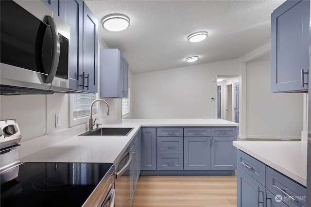 kitchen featuring kitchen peninsula, sink, stainless steel appliances, and a textured ceiling