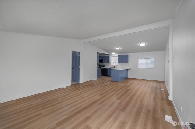 unfurnished living room with sink, lofted ceiling with beams, and light wood-type flooring