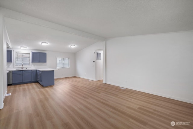 kitchen with sink, vaulted ceiling with beams, stainless steel dishwasher, and light wood-type flooring