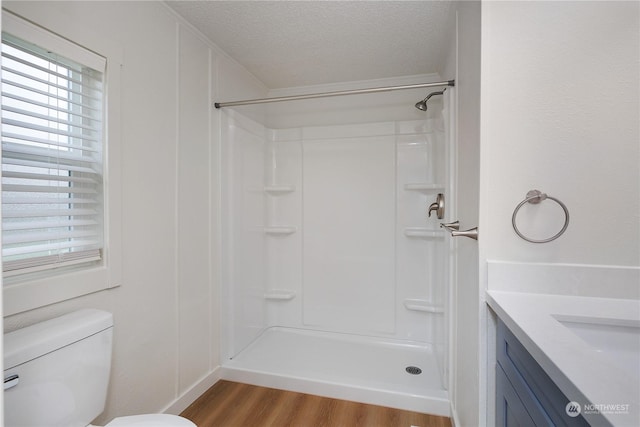 bathroom with toilet, wood-type flooring, a shower, and a textured ceiling